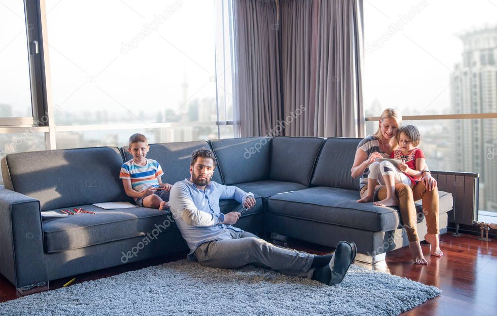 Happy Young Family Playing Together on sofa at home using a tablet and a children's drawing set