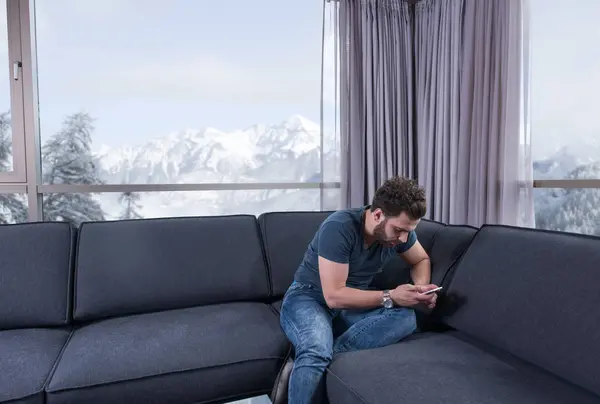 Young casual man using a mobile phone at home — Stock Photo, Image