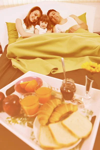 Mutlu genç aile kahvaltısını yatakta yer. — Stok fotoğraf