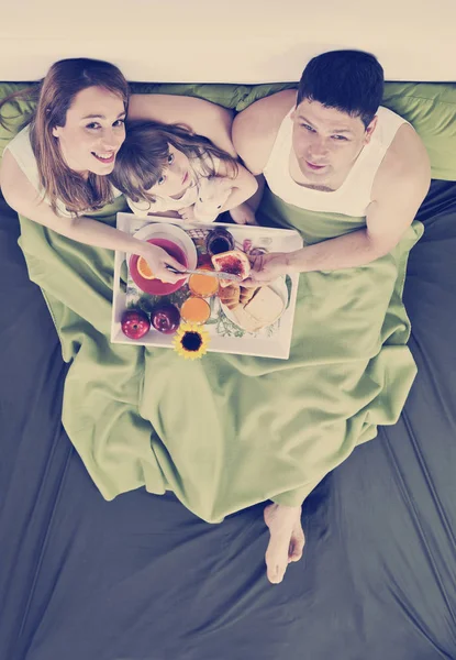 Happy young family eat breakfast in bed — Stock Photo, Image