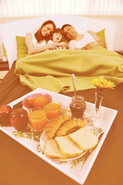 Glad ung familj äter frukost på sängen — Stockfoto