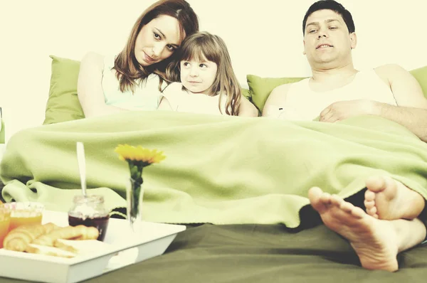 Happy young family eat breakfast in bed — Stock Photo, Image