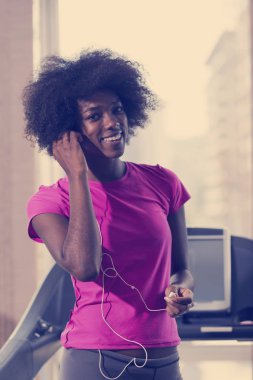 bir koşu bandı üzerinde çalışan afro Amerikalı kadın