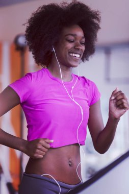 bir koşu bandı üzerinde çalışan afro Amerikalı kadın