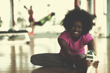 mutlu genç Afro-Amerikan kadın bir spor salonu ve germe egzersiz genç mab arka planda dumbbells ile egzersiz öncesine Isınma