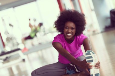 mutlu genç Afro-Amerikan kadın bir spor salonu ve germe egzersiz genç mab arka planda dumbbells ile egzersiz öncesine Isınma