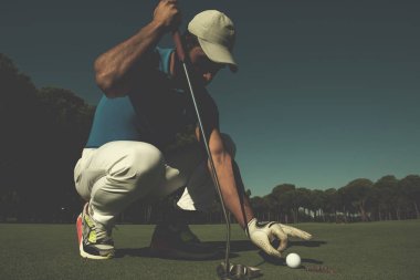 Golf topu deliğe koyarak elini