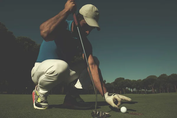 Mano del hombre poniendo pelota de golf en el agujero — Foto de Stock