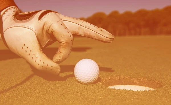 Mans Hand sätta golfboll i hål — Stockfoto