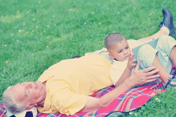 Dědeček a dítě v parku pomocí tabletu — Stock fotografie