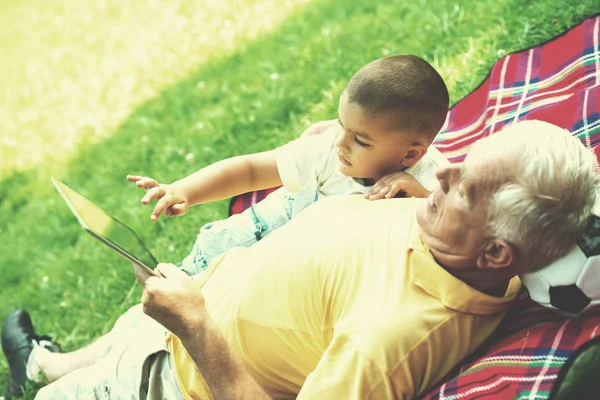 Dziadek i dziecko w parku za pomocą tabletu — Zdjęcie stockowe