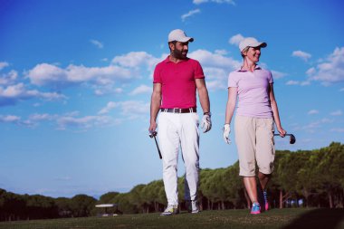 Genç çift golf sahasındaki bir sonraki deliğe yürüyor.