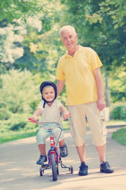 Mutlu büyükbaba ve çocuk güzel güneşli bir günde parkta eğlenip oynuyorlar.