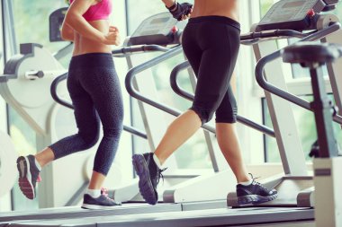 Spor, spor, spor, yaşam tarzı, teknoloji ve insan konsepti. Spor salonunda koşu bandında egzersiz yapan gülümseyen kadın.