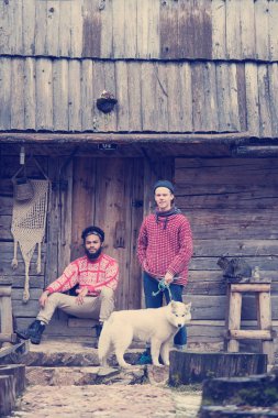 hipsters çift dikey, iki genç adam ile eski ahşap retro evinin önünde oturan beyaz husky köpek
