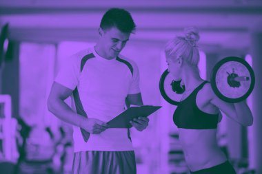 Spor antrenörü olan genç bir kadın spor salonu ikilisi gibi ağırlık kaldırıyor.