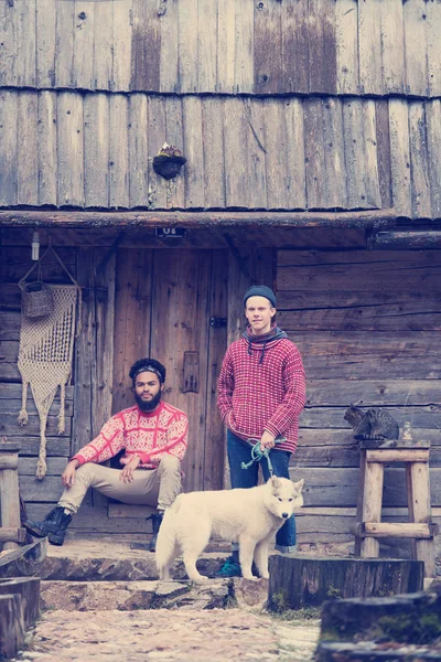 赶时髦的人夫妇画像 白赫斯基狗坐在旧木复古房子前面的两个年轻人 — 图库照片