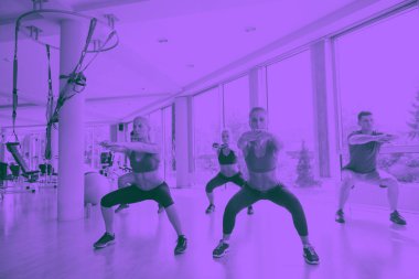 Spor salonunda spor yapan bir grup genç insan.