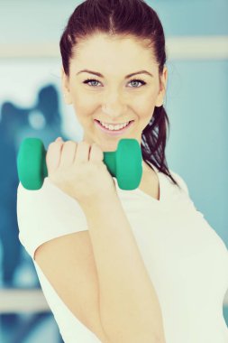 Güzel, genç bir kadın spor kulübünde ağırlık çalışıyor.