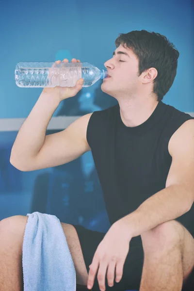 若い男がスポーツクラブでフィットネストレーニングで水を飲む — ストック写真