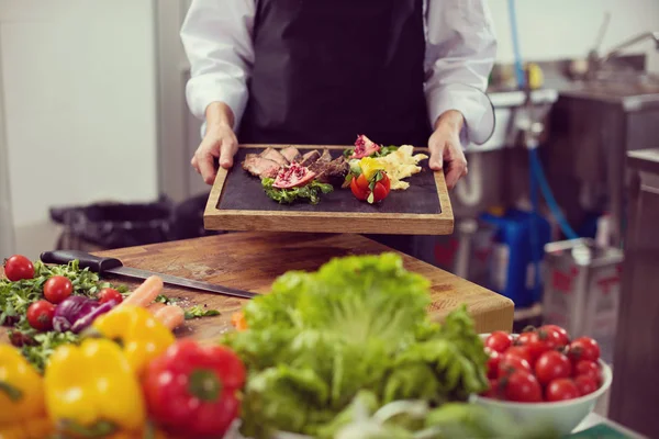 Chef fêmea segurando prato de bife de carne — Fotografia de Stock