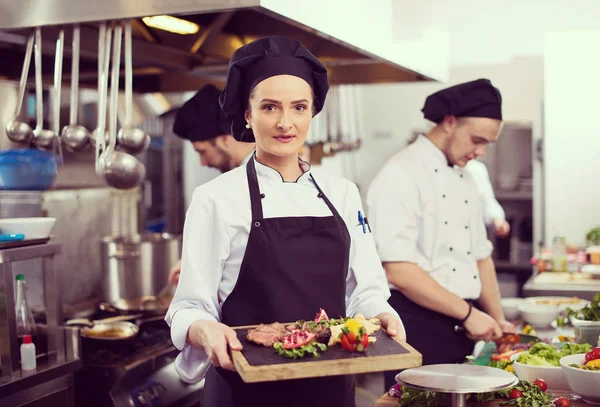 宾馆或餐厅厨房的女厨师拿着烤牛肉牛排盘和蔬菜装饰 — 图库照片