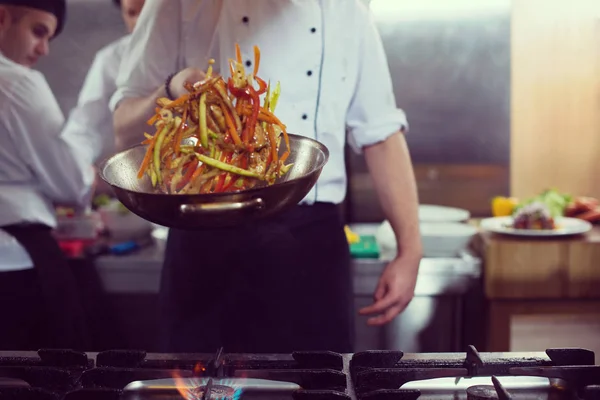 Chef lançando legumes em wok — Fotografia de Stock