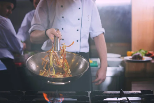 Chef lançando legumes em wok — Fotografia de Stock