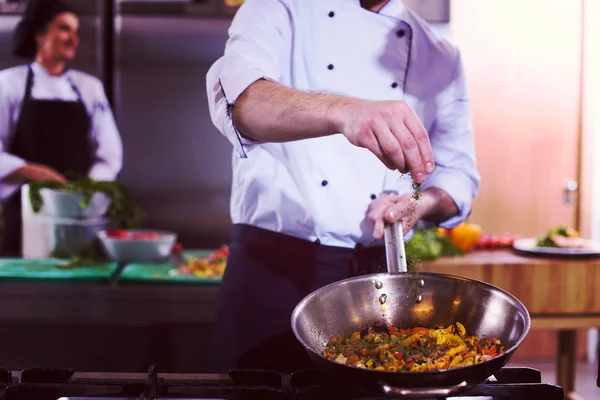 Chef putting spices on vegetables in wok — Stock Photo, Image