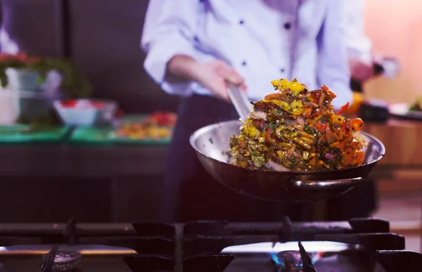 Chef lançando legumes em wok — Fotografia de Stock