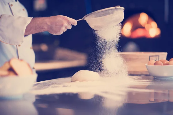 Шеф-кухар, що посипає борошно над свіжим тістом для піци — стокове фото