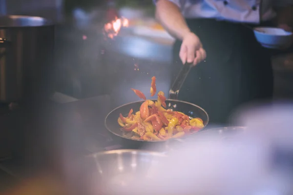 Chef lançando legumes em wok — Fotografia de Stock