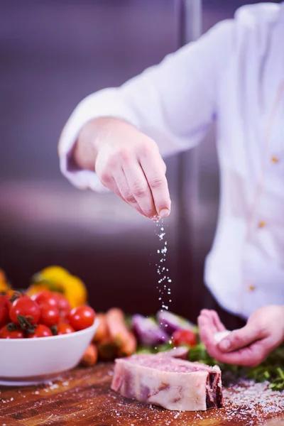 Chef colocando sal em fatias suculentas de bife cru — Fotografia de Stock