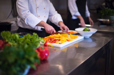 Aşçı taze ve lezzetli sebzeleri yemek veya salata için kesiyor.