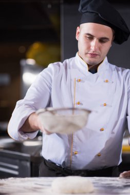 Şef mutfak masasına taze pizza hamuru serpiyor.