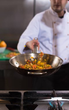 Genç erkek aşçı, ticari mutfakta sebze çeviriyor.