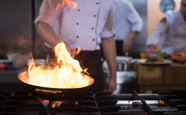 シェフの料理とレストランのキッチンで食べ物に炎を行う — ストック写真