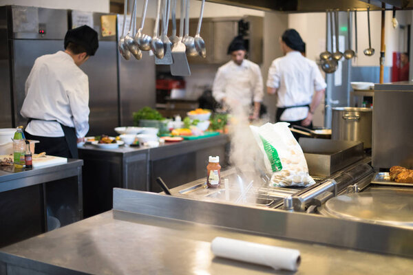 Professional team cooks and chefs preparing meals at busy hotel or restaurant  kitchen