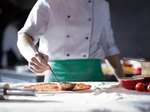 Koch schmiert Pizzateig mit Ketchup — Stockfoto