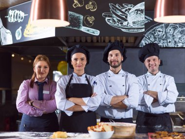 Restoranın ticari mutfağında bir arada duran grup şeflerinin portresi.