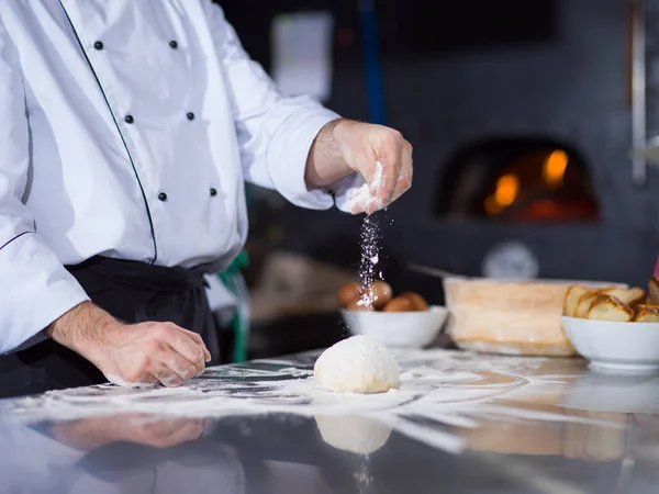 Şef taze pizza hamurunun üzerine un serpiyor. — Stok fotoğraf