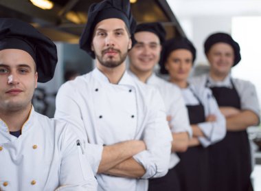 Restoranın ticari mutfağında bir arada duran grup şeflerinin portresi.
