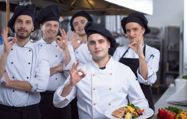 Restoranın ticari mutfağında bir arada duran grup şeflerinin portresi.