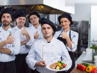 Restoranın ticari mutfağında bir arada duran grup şeflerinin portresi.