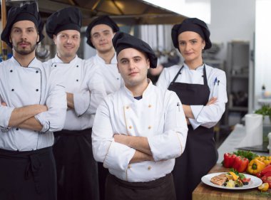 Restoranın ticari mutfağında bir arada duran grup şeflerinin portresi.