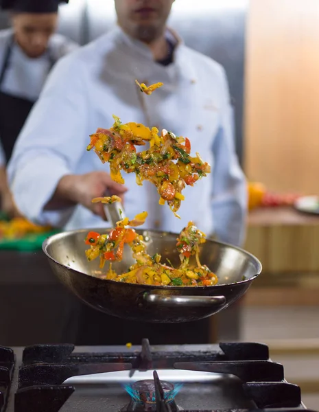 Chef lançando legumes em wok — Fotografia de Stock