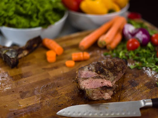 Juicy slices of grilled steak on wooden board — Stock Photo, Image