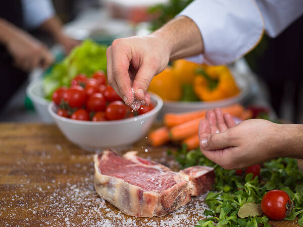 Chef putting salt on juicy slice of raw steak