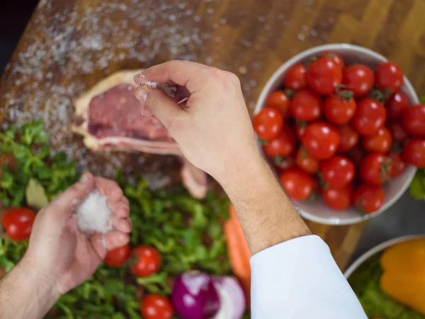 Chef colocando sal em fatias suculentas de bife cru — Fotografia de Stock