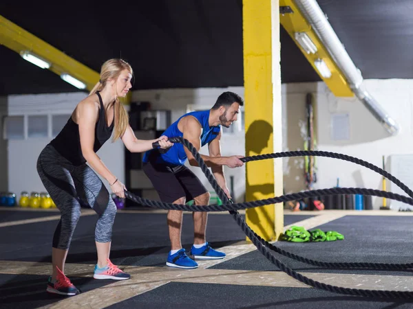 Sports couple doing battle ropes crossfitness exercise — Stock Photo, Image